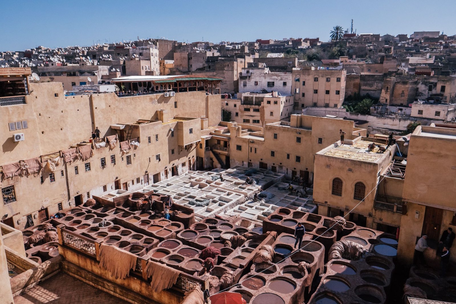 The high-angle view of the cityscape and traditional tannery vats on a sunny day in Fes